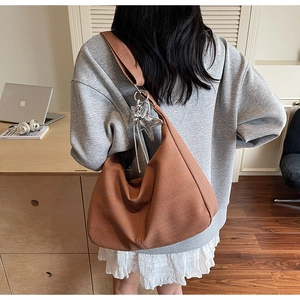 Close-up of brown knit tote bag with V-shaped texture and silver star charm detail