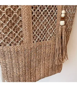 Detail of woven straw tote bag featuring intricate mesh patterns and beaded tassels