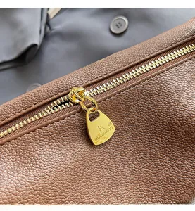 Close-up of premium brown litchi grain leather bag with smooth golden metal zipper detail