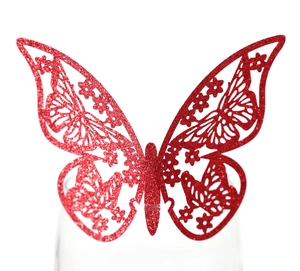 Detalle de una mariposa decorativa 3D con purpurina roja en el borde de una copa