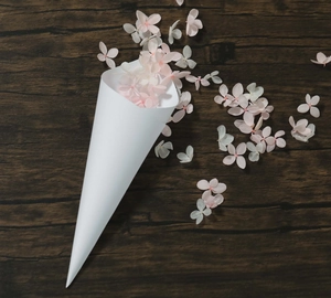 Detail of white kraft paper wedding cone with elegant pink and white dried flower petals