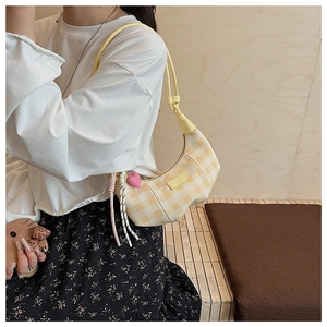 Detail of checkered crescent bag with yellow leather strap and heart charm pendant