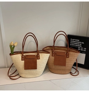 Detailed view of large straw tote bag featuring brown leather pockets and sturdy handles