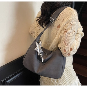 Detail of grey dumpling tote bag with a silver star charm worn with a knit sweater