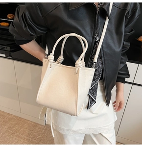 Detailed close-up of cream lychee texture leather bucket bag with braided knot handle