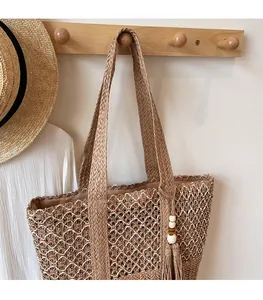 Macro view of woven straw beach bag detail with hollow pattern and tassel pendant