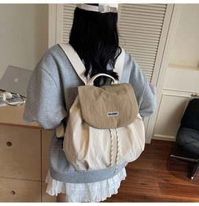 Detail of a minimalist cream nylon backpack with khaki flap and black-white drawstring cord