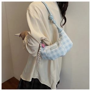 Detail of blue plaid crescent bag with knot strap and pink heart charm accessory