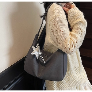 Detail of dark grey knitted hobo bag with star pendant shown on a casual model outfit