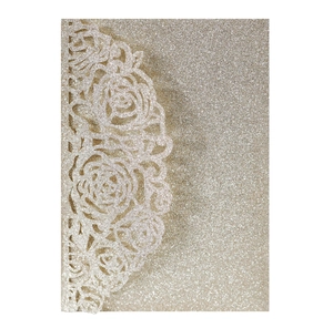 Detail of laser-cut rose patterns on champagne gold glitter paper wedding invitation