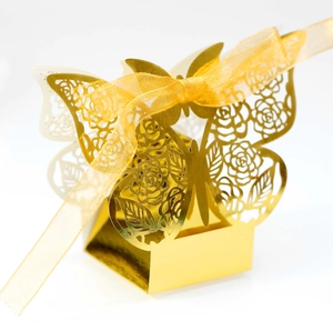 Detail of laser-cut rose patterns and organza ribbon on golden butterfly candy box