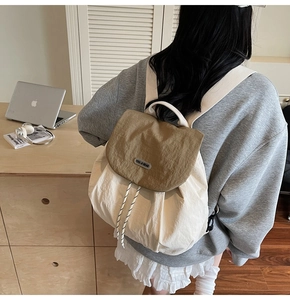 Rear view of a stylish khaki and beige drawstring backpack worn in a cozy home office setup