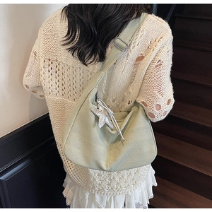 Detail of light green woven dumpling bag with wide strap and silver star pendant