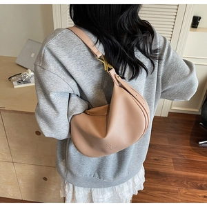 Detail of apricot hobo bag with gold X-shaped hardware and logo on textured leather