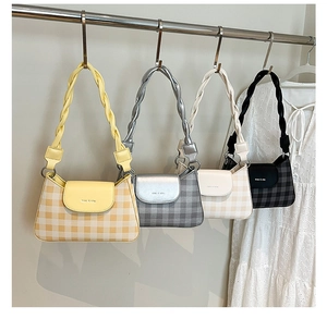 Plaid underarm bags in four colors with twisted shoulder straps displayed in a boutique