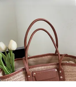 Close-up of woven straw tote bag with leather straps and gold rivet detailing
