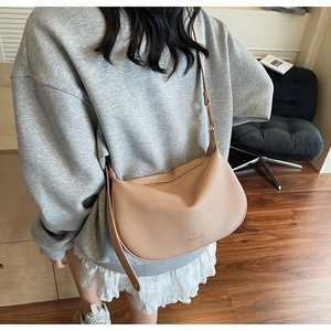 Detail view of beige half-moon crossbody bag with adjustable strap and brand logo