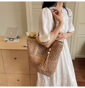 Close-up of woven straw tote bag featuring intricate mesh patterns and wood bead tassel