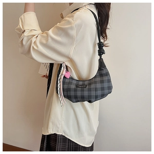 Detail of grey plaid crescent bag with pink heart charm and unique knotted shoulder strap