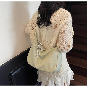 Close-up of light green canvas tote bag featuring a silver star pendant and soft texture