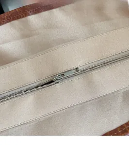 Close-up of smooth silver zipper detail and durable canvas lining on a straw tote bag