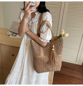 Detail of woven straw tote bag with long tassels and beads on white vintage dress