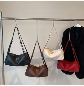 Detailed group view of colorful leather shoulder bags hanging against a minimalist wall
