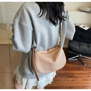 Detail of a light pink leather half-moon Hobo bag with adjustable strap and gold hardware