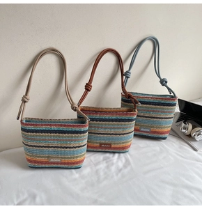 Trois sacs seaux tissés bohèmes à rayures colorées et bandoulières en cuir sur fond blanc