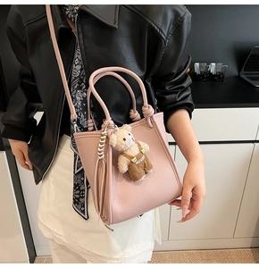 Pink lychee texture bucket bag shown on a model with a teddy bear charm detail