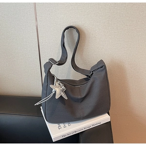 Close-up of dark grey herringbone texture tote bag with a silver star pendant detail