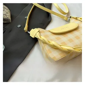 Detail of yellow and white checkered crossbody bag with braided leather side decor