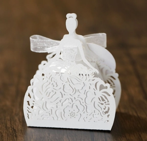 Macro detail of laser-cut white favor box showing elegant hollow flower patterns and ribbon