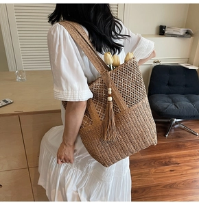 Close-up of handmade woven straw tote bag with wood bead tassel and natural texture