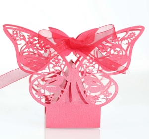 Close-up of pink laser-cut butterfly favor box with intricate patterns and silk ribbon