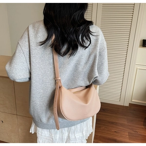 Detail view of pink hobo bag with pebble leather texture and adjustable strap worn by model