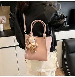 Detail of pink lychee leather bucket bag with cute bear pendant worn by a model