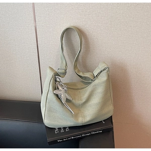 Detail of light green fabric tote bag featuring a silver starfish charm and zipper closure