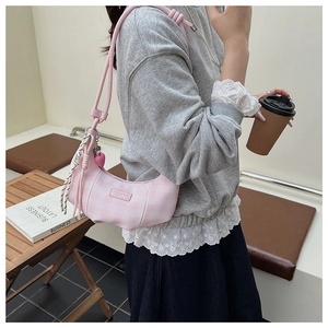 Pink and white checkered crescent underarm bag with a cute heart charm shown on model