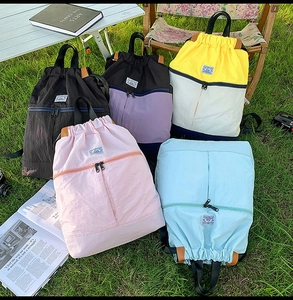 Outdoor backpacks in five colors displayed on a lawn for camping and travel use