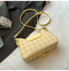 Detail of yellow gingham shoulder bag with adjustable strap on textured background