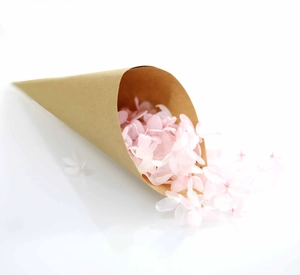 Close-up of pink hydrangea petals inside a kraft paper cone for wedding confetti