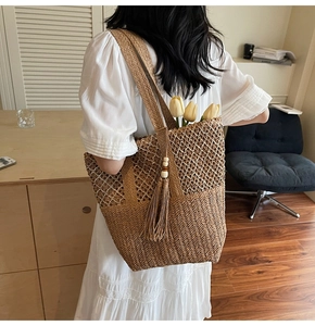 Detailed macro view of woven straw beach tote bag featuring decorative fringe and yellow tulips