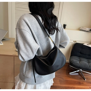 Detail of black lychee grain leather hobo bag with adjustable strap in home office setting