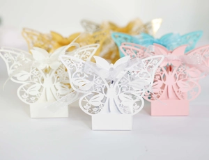Close-up of laser-cut butterfly wedding favor boxes with organza ribbons in multi-colors