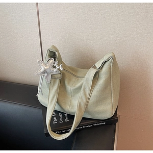 Detailed view of light green woven tote bag with a silver star pendant accessory