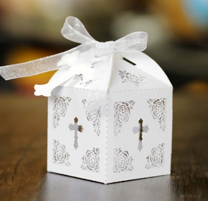 Detailed laser-cut cross and rose patterns on white cardboard favor box with silk ribbon