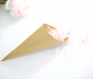 Close-up of kraft paper wedding confetti cone filled with elegant pink flower petals