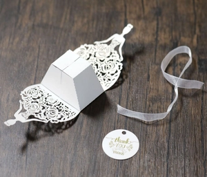 Detailed laser-cut bridal dress wedding favor box with white ribbon and thank you tag