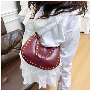 Detail of burgundy hobo bag with vintage texture, gold rivets and chain strap